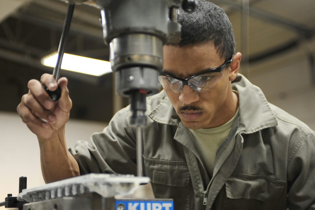 Worker drilling a hole into a metal bar